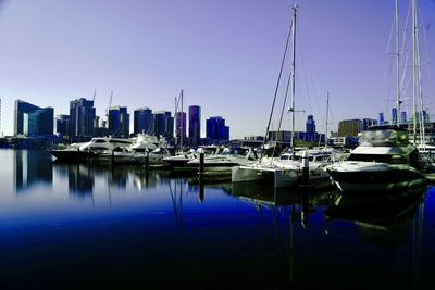 Sailboats moored in harbor against clear sky