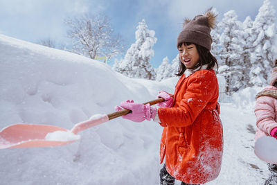 Portrait of smiling young woman skiing on snow covered field