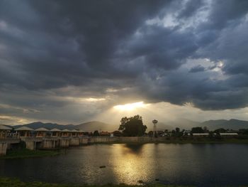 River by buildings against sky at sunset