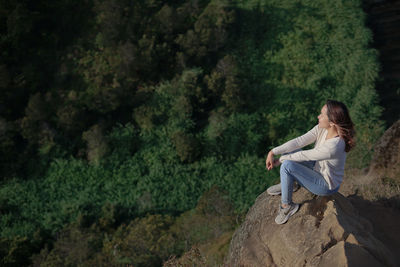 Woman sitting on rock of a mountain