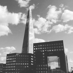 Low angle view of skyscrapers against cloudy sky