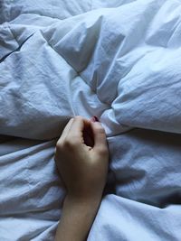 Cropped hand of woman on bed