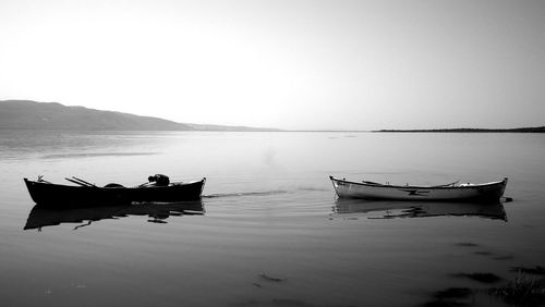 Side view of man in boat moored on sea against clear sky