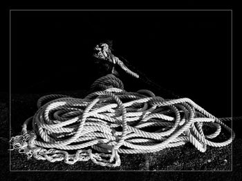 Close-up of rope tied on wood against black background