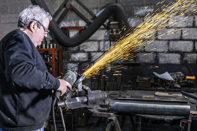 Man cutting metal with circular saw in factory