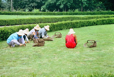 Gardeners working while crouching on grass