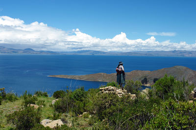Woman standing by sea against sky
