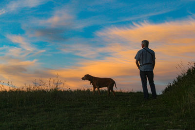 Man and dog on field at sunset 