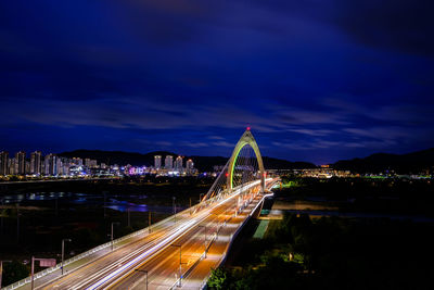 Illuminated bridge over river against sky at night