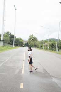 Side view of woman running on road against sky