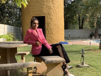 Portrait of woman sitting on seat against trees