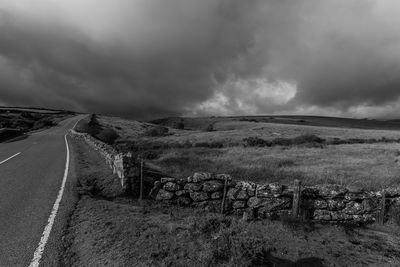 Empty road amidst field against sky