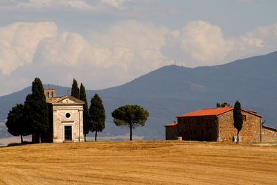 Houses on field by mountains against sky