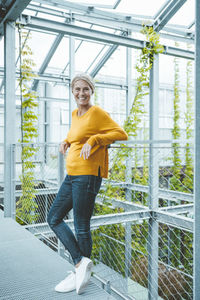 Happy agronomist standing in corridor at greenhouse