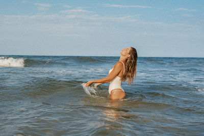 Rear view of woman in sea against sky