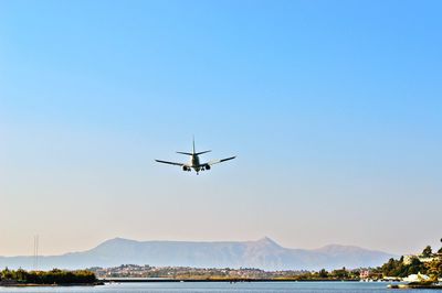 Low angle view of airplane flying and landing on corfu island