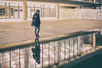 Full length of woman reflecting in water at habima square during night