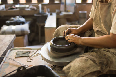 Midsection of man making pot in workshop
