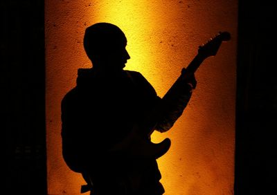 Silhouette man standing against orange wall