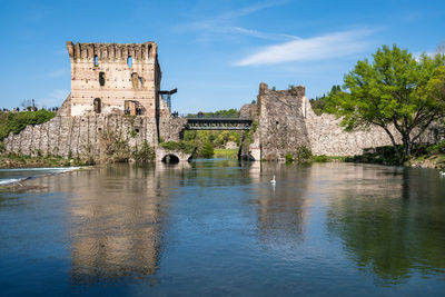Ruins of visconti bridge reflecting into the water at borghetto sul mincio, italy