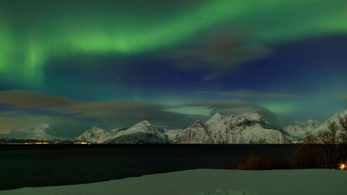 Scenic view of lake by mountains against sky at night