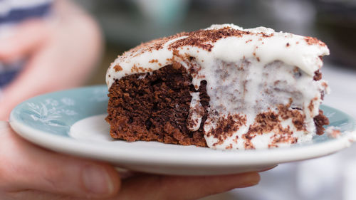 Close-up of hand holding cake slice in plate