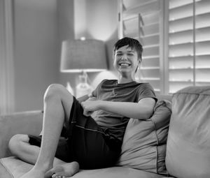 Young woman sitting on bed at home