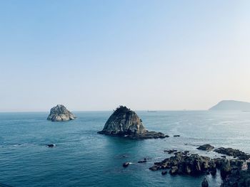 Scenic view of rocks in sea against clear sky