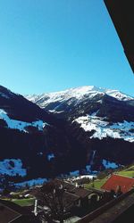 Scenic view of snow covered mountains against clear blue sky