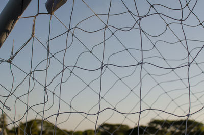 Close-up of chainlink fence on field against sky