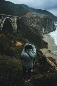 Rear view of man photographing bridge