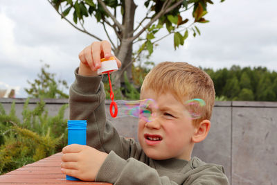 The blond boy squinted his eyes and makes soap bubbles. five year old boy in soap bubbles.