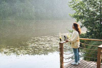 Rear view of woman standing by lake