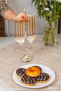 Hand holding candle by food on table