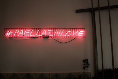 Low angle view of illuminated information sign on wall at night