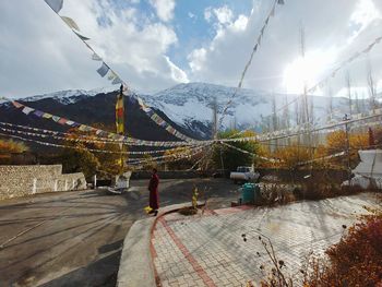 Man looking away while standing below prayer flags on footpath 