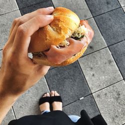 Low section of woman holding burger on footpath