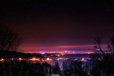 Silhouette trees and landscape against sky at night