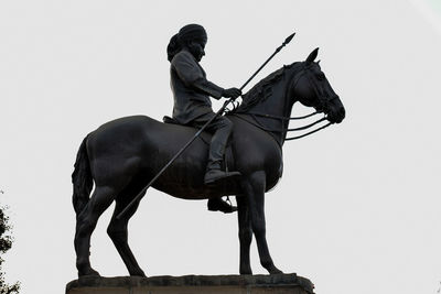 Statue of man riding horse against sky