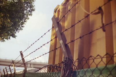 Low angle view of barbed wire fence against sky