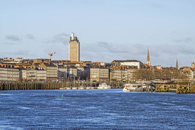 Sea by buildings against sky in city