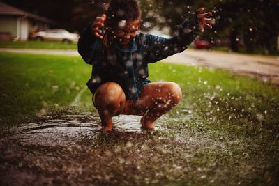 Girl playing in puddle at lawn during rainy season