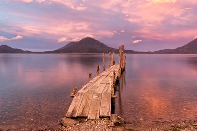 Pier over lake against sky during sunset