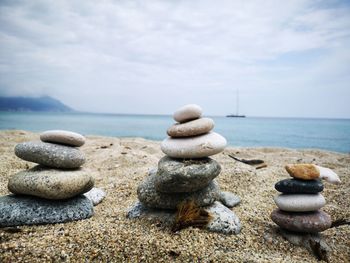 Stack of stones on beach against sky