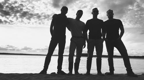 Silhouette people on beach against sky