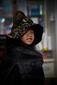 Portrait of smiling girl wearing witch at home