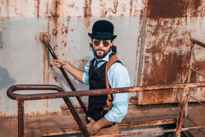 Portrait of young man holding metal against wall