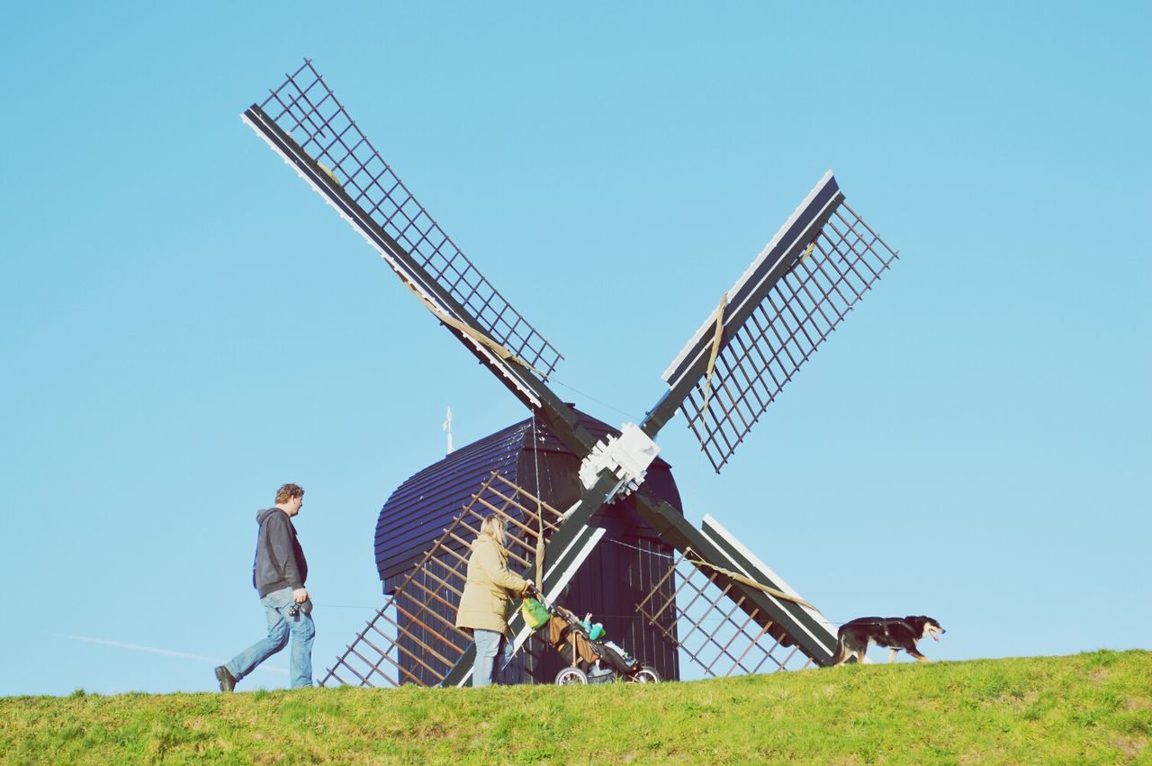 clear sky, traditional windmill, alternative energy, windmill, renewable energy, wind power, low angle view, wind turbine, environmental conservation, crane - construction machinery, construction site, technology, fuel and power generation, built structure, field, copy space, development, blue, architecture, grass