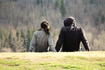 Rear view of couple reclining on field