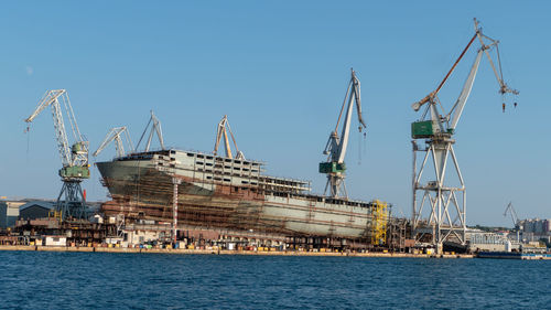 Cranes at commercial dock against clear sky